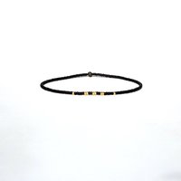 A thin minimalist style miyuki stretch bracelet in matte black and gold color