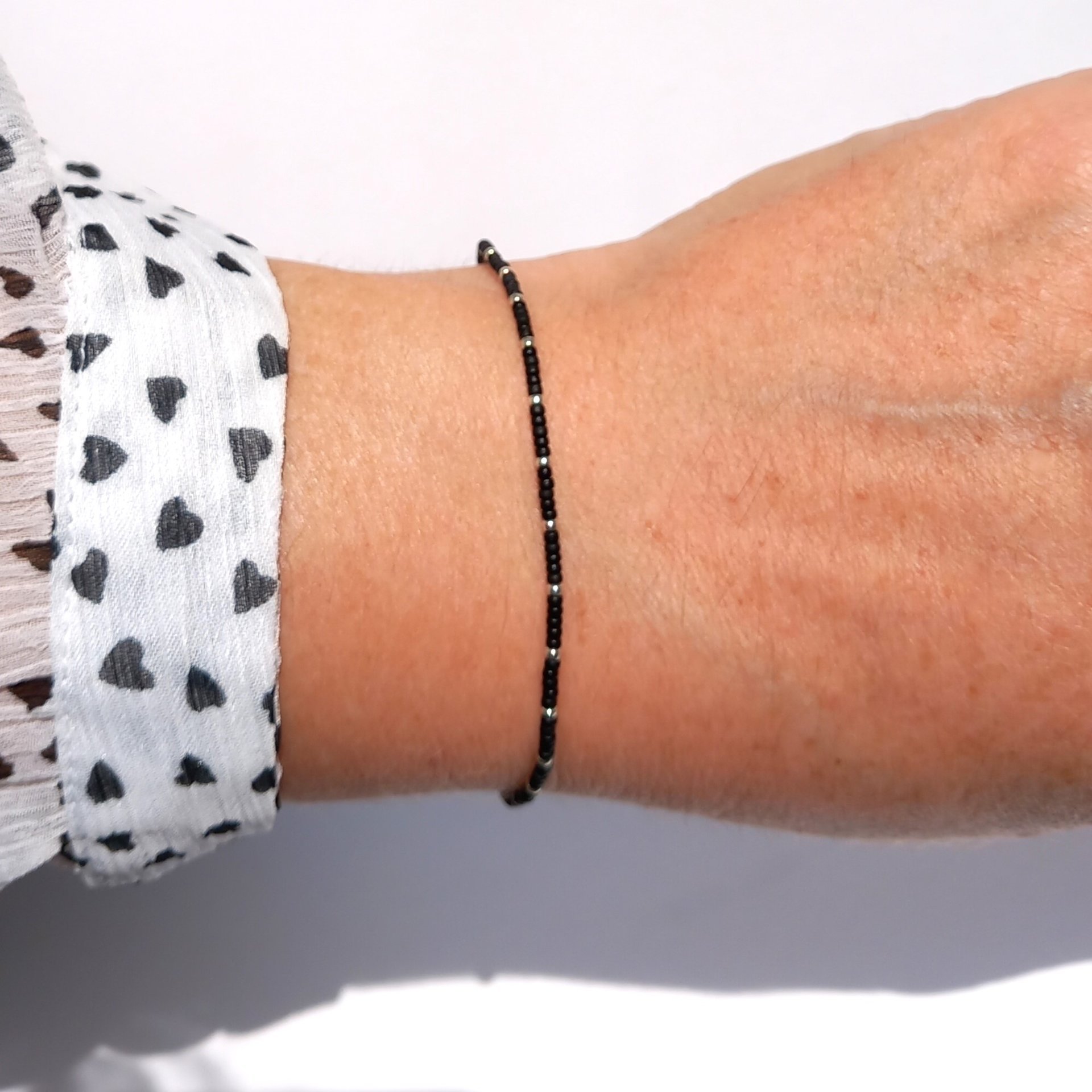 Thin miyuki stretch bracelet of tiny rocaille beads in black and silver color, minimalist style, light, seed beads