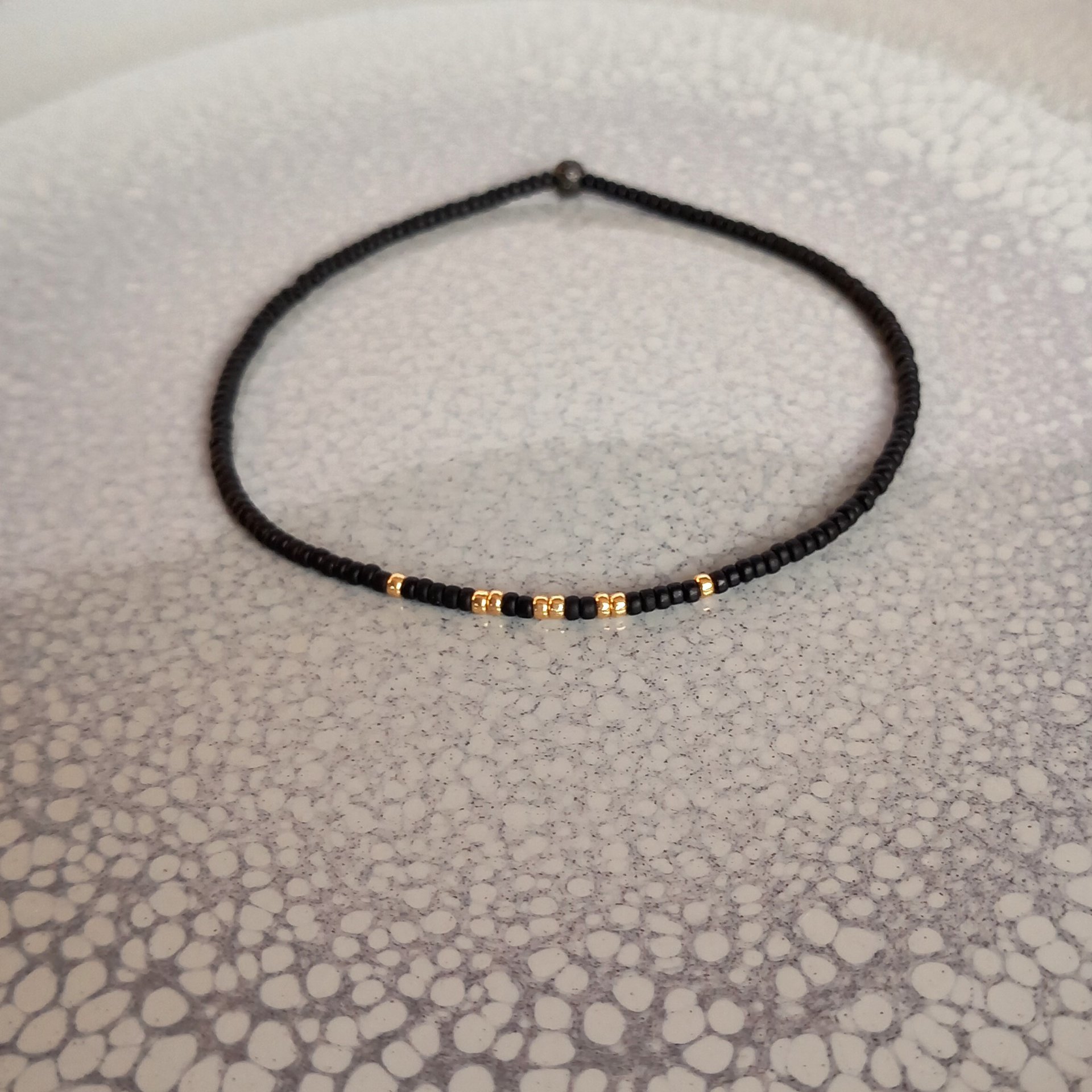 Thin miyuki stretch bracelets with matte black, gold, silver and bronze color tiny beads, four designs in minimalist style