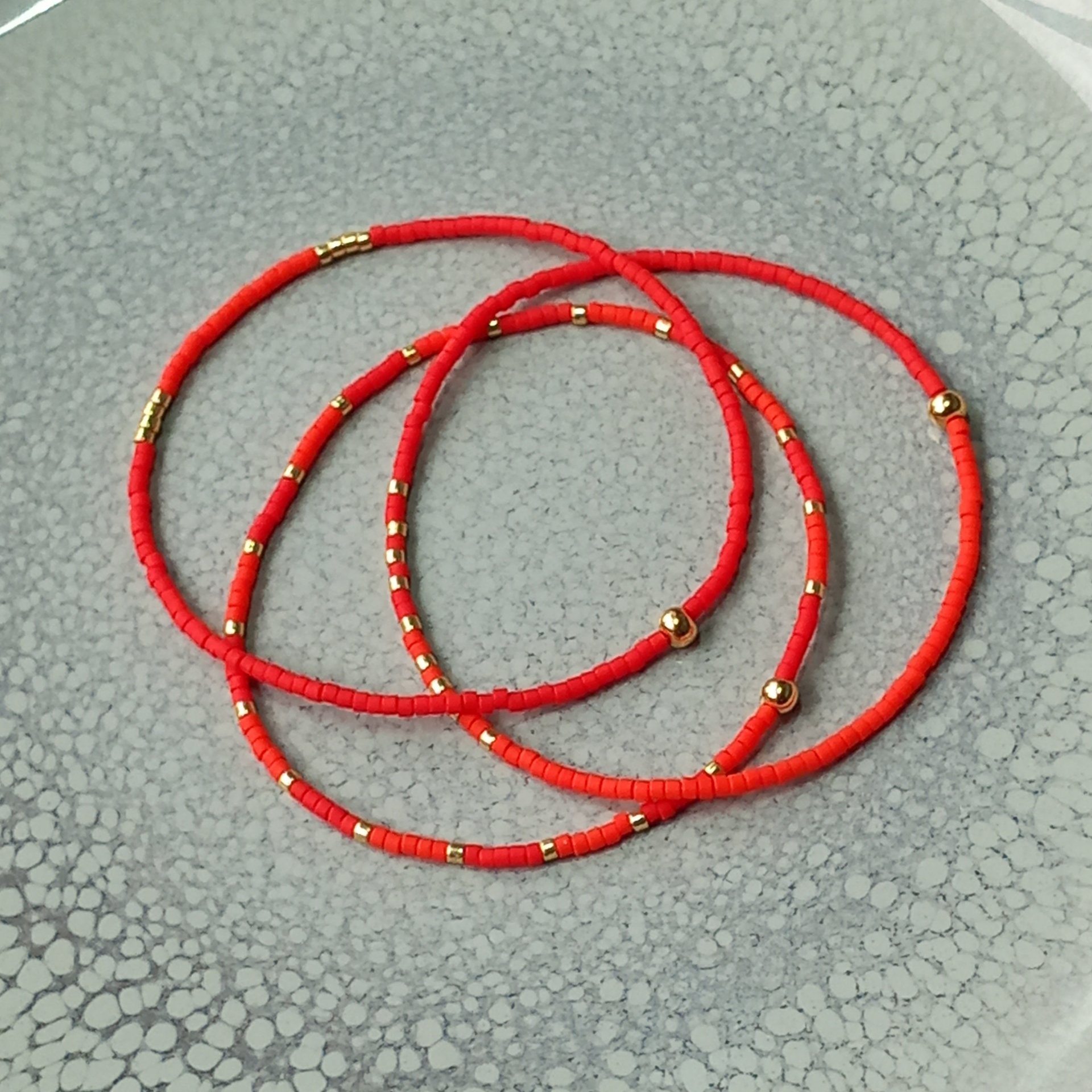 Delicate miyuki stretch bracelet in red with gold color accents, single or a set of bracelets, comfortable and light