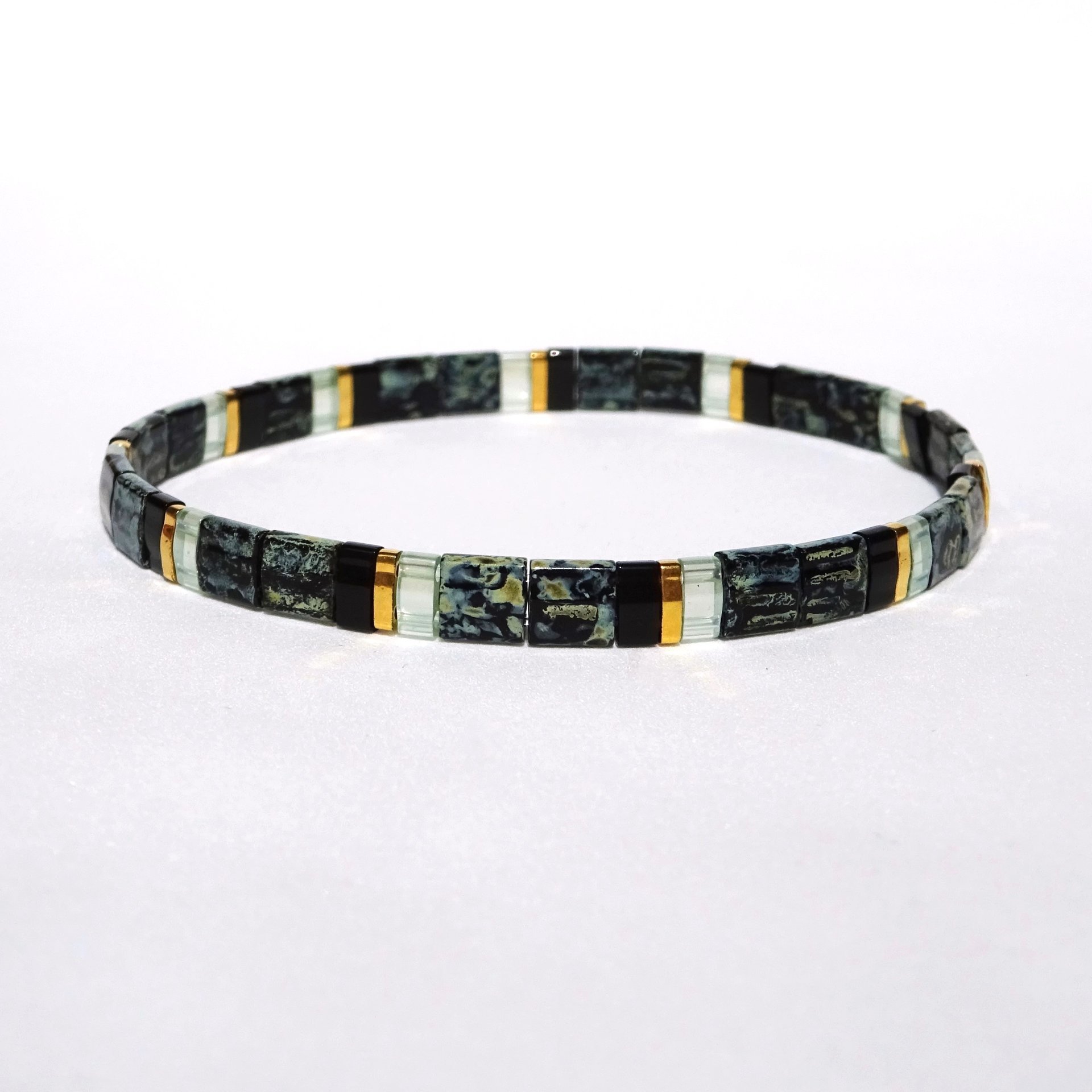 Elegant miyuki tila beads bracelet strung on transparent stretch cord with black and gold-plated tila beads