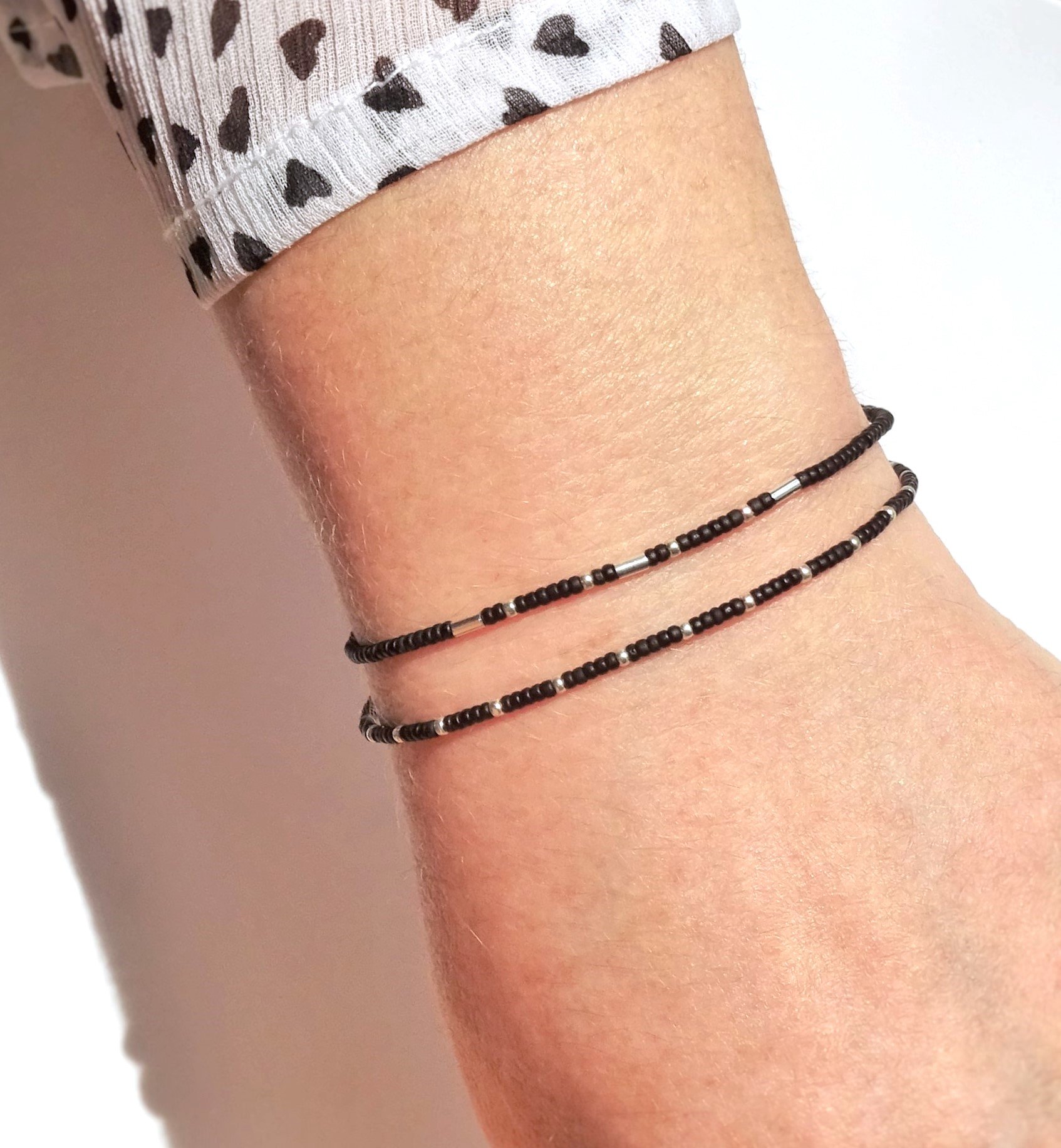 A set of two thin miyuki stretch bracelets made with tiny rocaille beads in black and silver color, minimalist style, light, seed beads