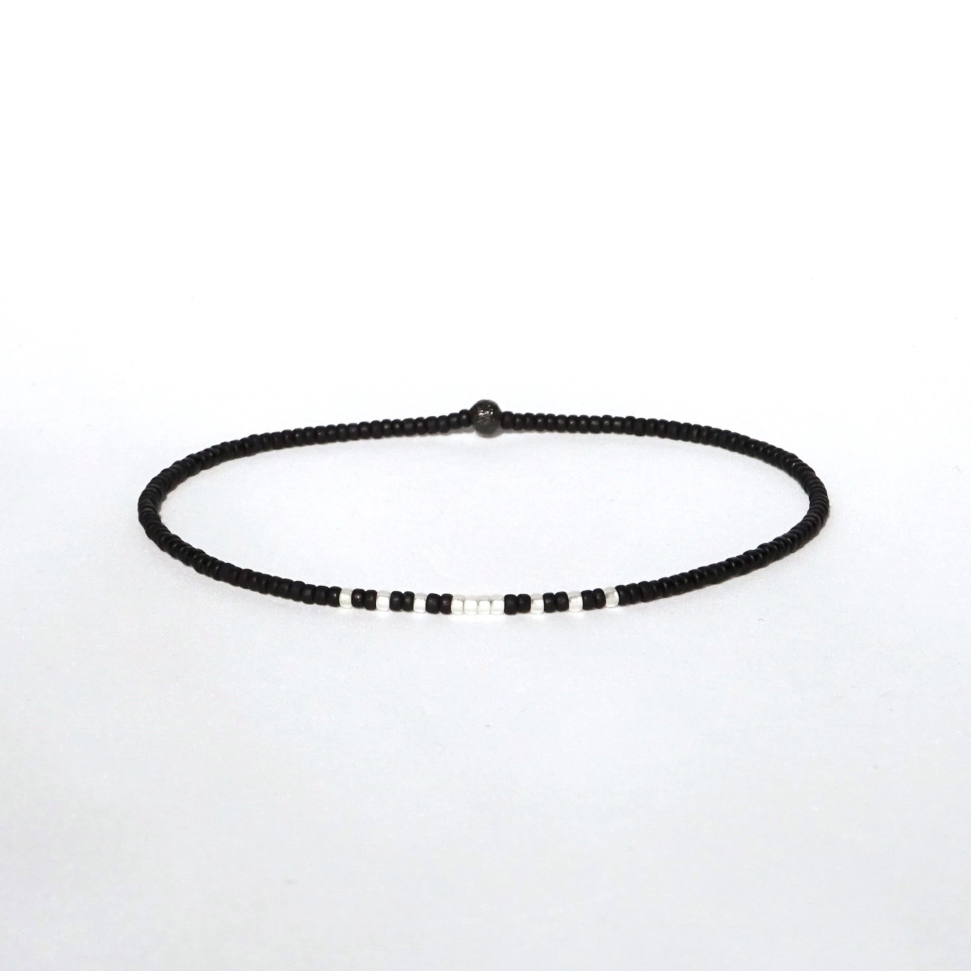 A thin minimalist style miyuki stretch bracelet in matte black and silverlined white