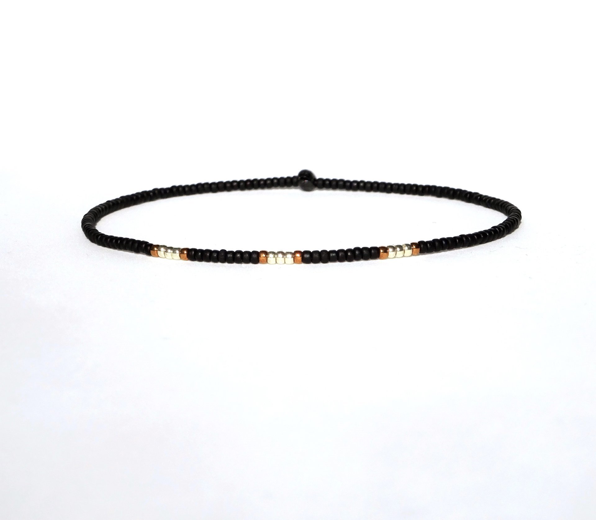 A thin minimalist style miyuki stretch bracelet in matte black, gold and bronze color